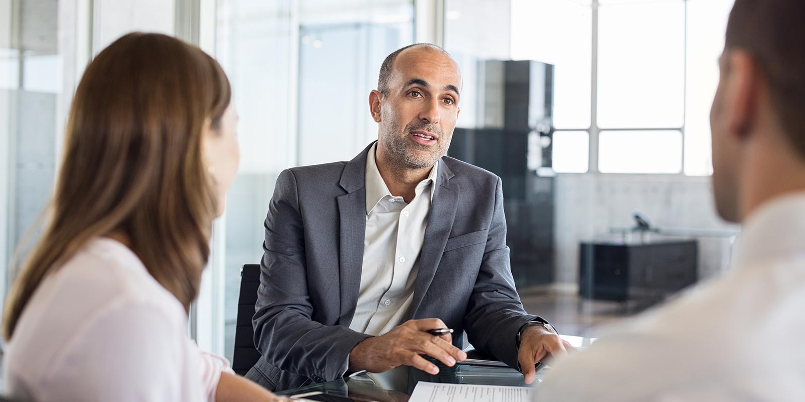 business man talking to a couple in his office