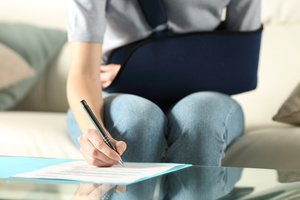 A woman with a sling signing a document