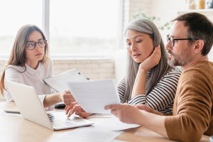 An elderly couple checking insurance plans with a female agent