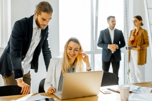 group of employees gathering around a laptop to discuss strategies