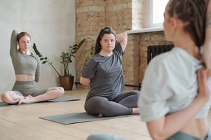 Two women in a yoga class with a female teacher