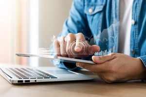 A man calculating his investments in a tablet and a laptop