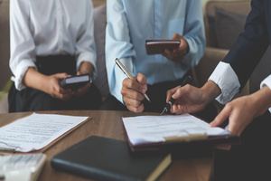 Two employees signing a document for an insurance agent