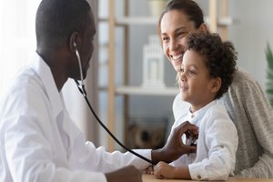 A black doctor checking heartbeats of a boy, The boy's mother is with him