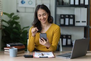 A woman checking policy gains in her mobile phone inside the office