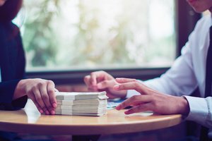 An insurance agent giving bundles of USD notes to someone